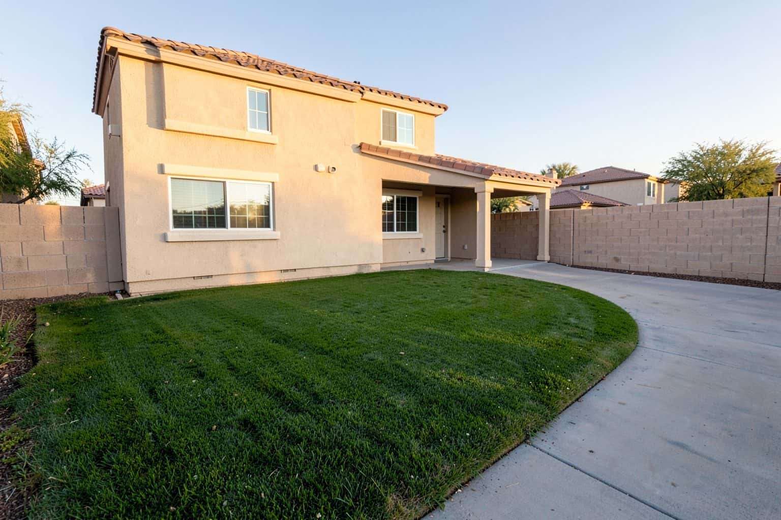 Sample yard: a two-story beige stucco house with a curved lawn beside the driveway